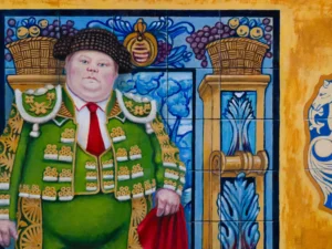 standing before blue tiled panels with a small brown dog at left and a black bull figure at right
